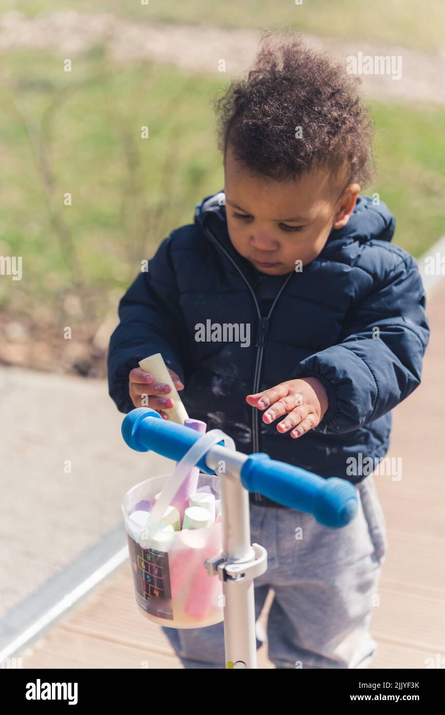 Fünf Jahre alter afroamerikanischer Junge mit einem cayon in der Hand und einem Roller. Hochwertige Fotos Stockfoto