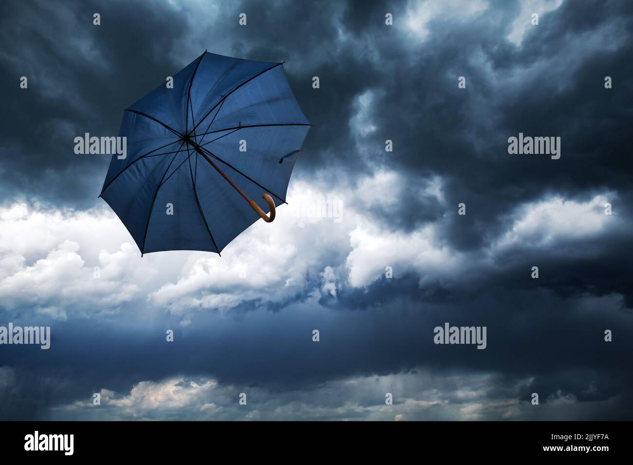 Fliegender blauer Regenschirm und wolkig-regnerischer Himmel aus der Nähe. Wetterprognose-Konzept Stockfoto