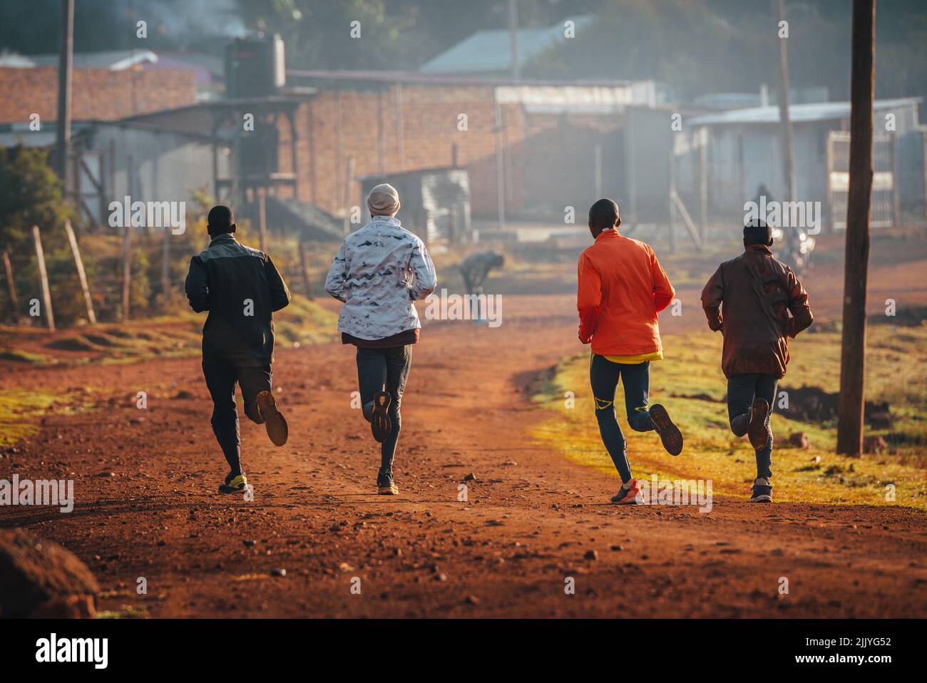 Lauftraining in Kenia. Eine Gruppe kenianischer Läufer bereitet sich auf einen Marathon vor und läuft auf rotem Boden. Marathonlauf, Leichtathletik. Einfaches Sportleben Stockfoto
