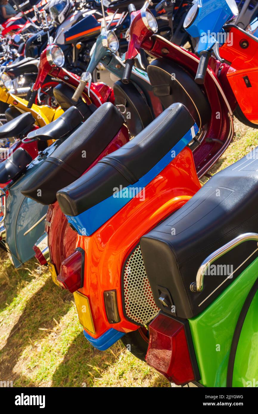Eine Reihe von bunten Mopeds, die auf dem Gras geparkt sind Stockfoto
