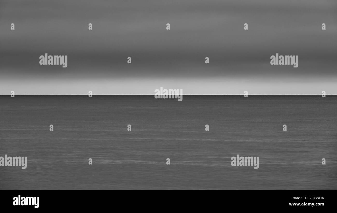 Eine Graustufe des Horizonts, die das Meer und den Himmel in gleiche Teile teilt Stockfoto