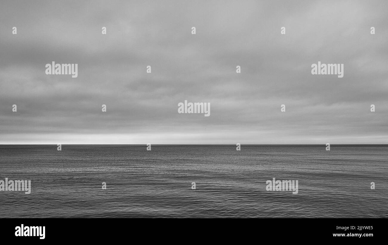 Eine Graustufen des Horizonts, die Meer und Himmel in gleiche Teile teilt, perfekt für Hintergrund oder Tapete Stockfoto