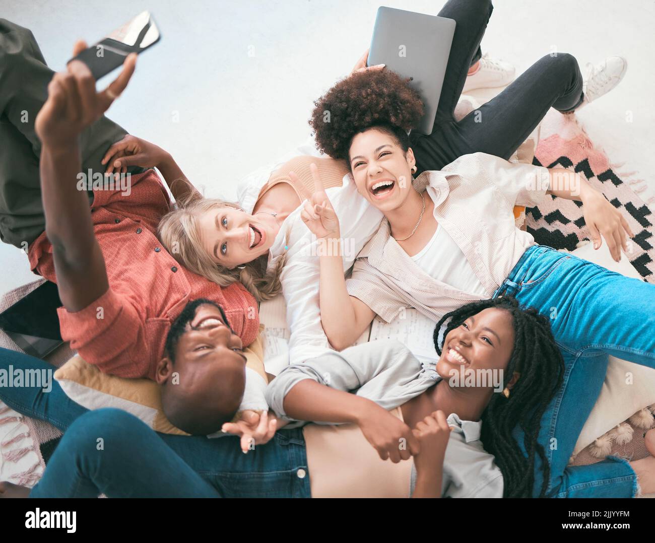 Ein begeistertes, kreatives Team nutzt ein Telefon für ein Selfie, während es sich entspannt, die Arbeit genießt und Spaß hat. Vielfältige Gruppe von Geschäftskollegen, die Teamarbeit zeigen Stockfoto