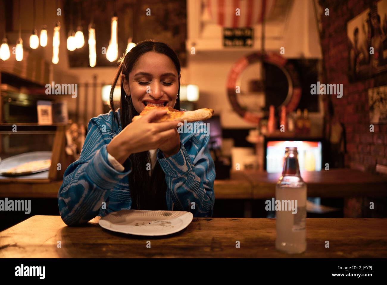 Pizza, Essen und Restaurant, in dem junge Frau Essen und Getränke genießt. Hungrige Frau, die abends in der Bar leckeres Essen hatte. Glücklich und Stockfoto