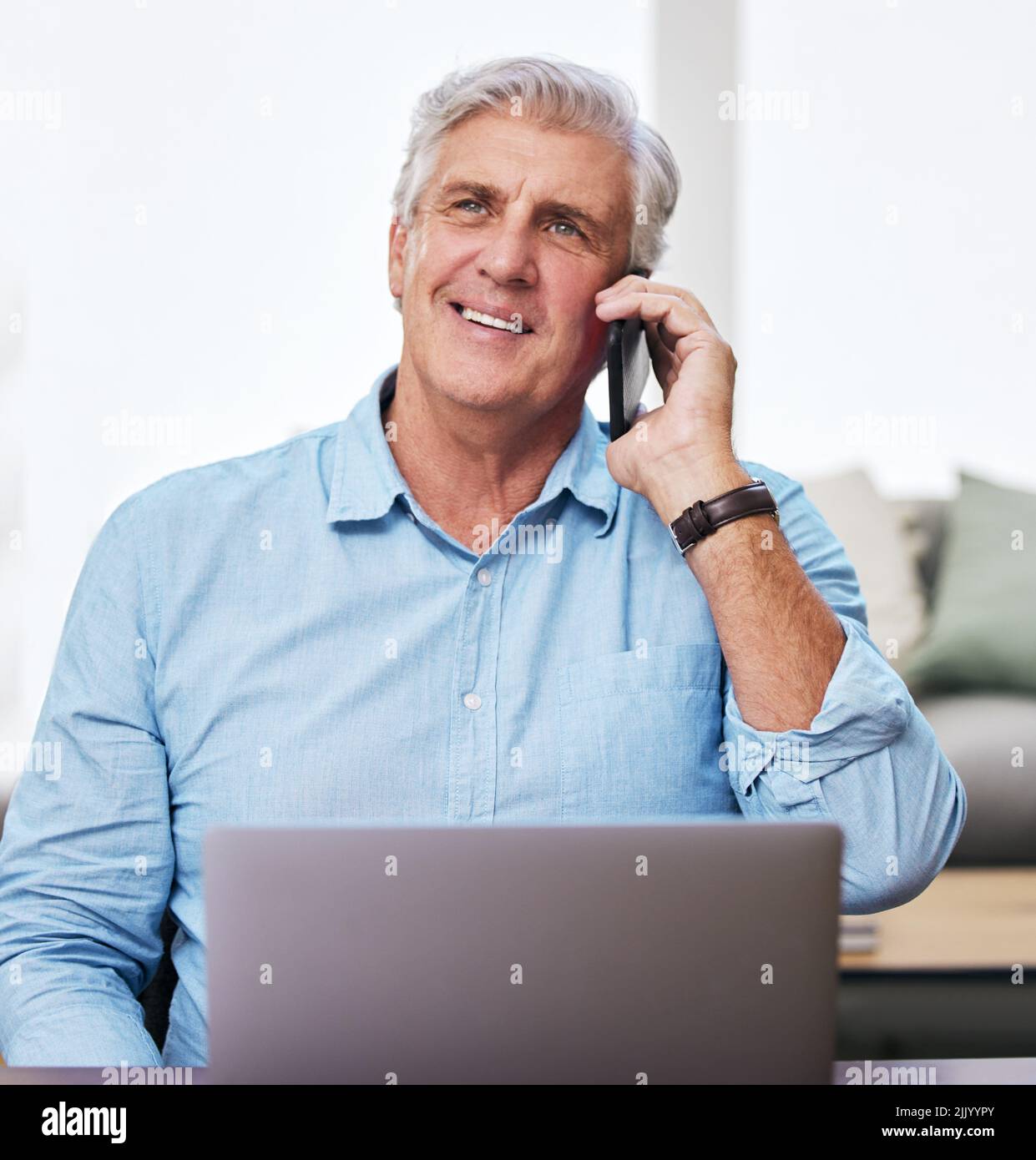 Arbeiten von zu Hause aus wie der Chef, den ich bin. Ein reifer Mann, der sein Handy und seinen Laptop benutzt, während er von zu Hause aus arbeitet. Stockfoto