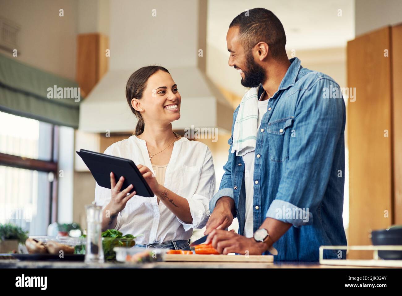 Ihr Food-Blog hat einige Anhänger. Ein junges Paar mit einem digitalen Tablet beim Kochen zu Hause. Stockfoto