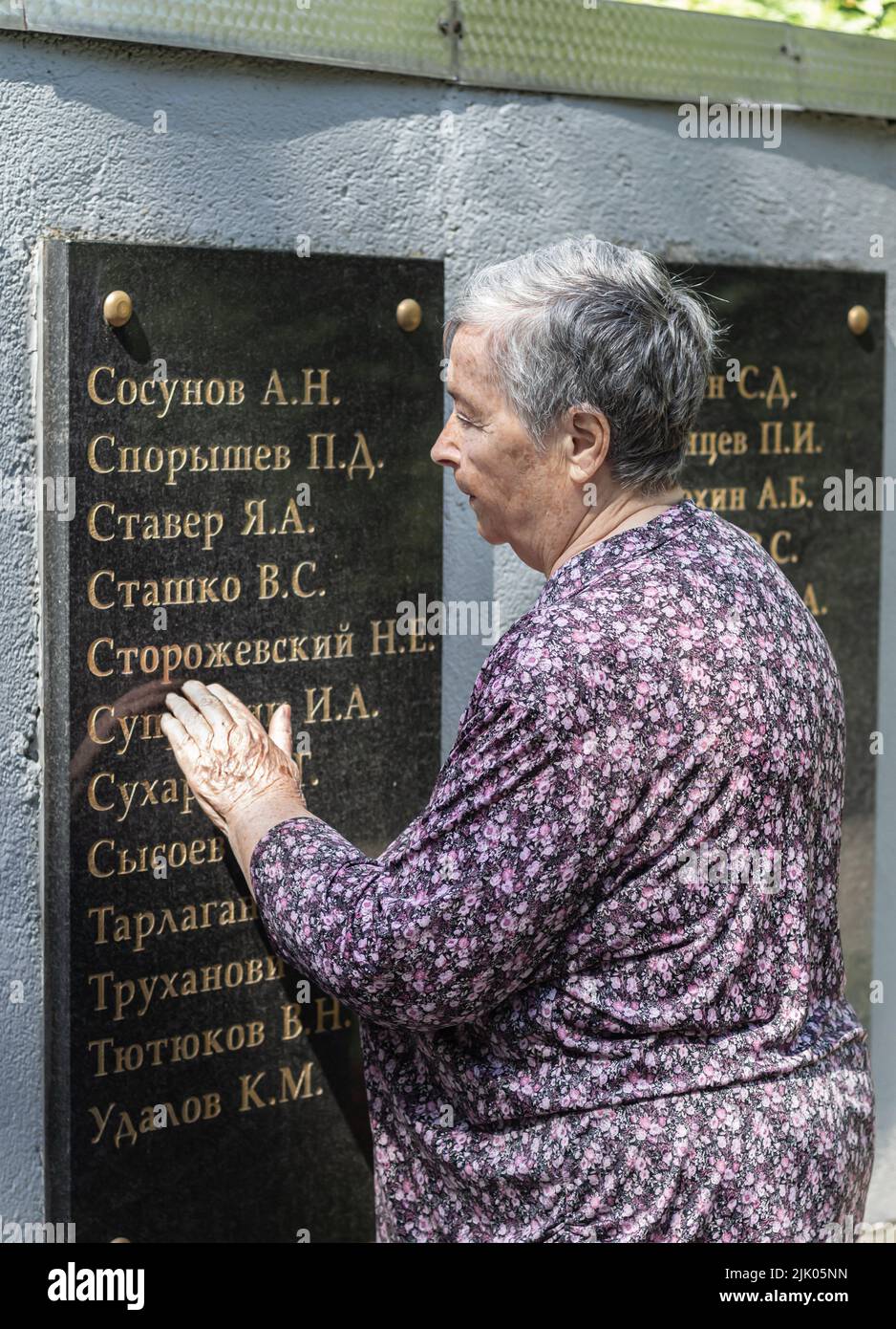Nahaufnahme des Porträts einer traurigen älteren Frau in der Nähe des Denkmals in Erinnerung an die Schüler starben die Lehrer der TSU im Krieg. Großmutter sucht Namen von Verwandten auf blac Stockfoto