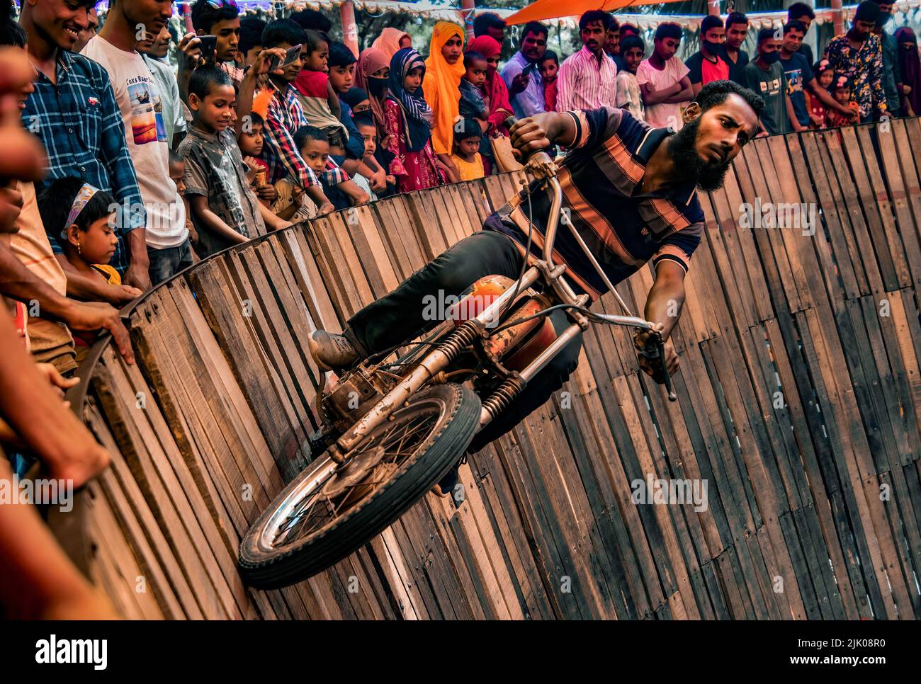 Waghalsige Motorradfahrer fahren 50 Meilen pro Stunde um eine steile „Todeswand“ mit einem Sozius hinter sich Stockfoto