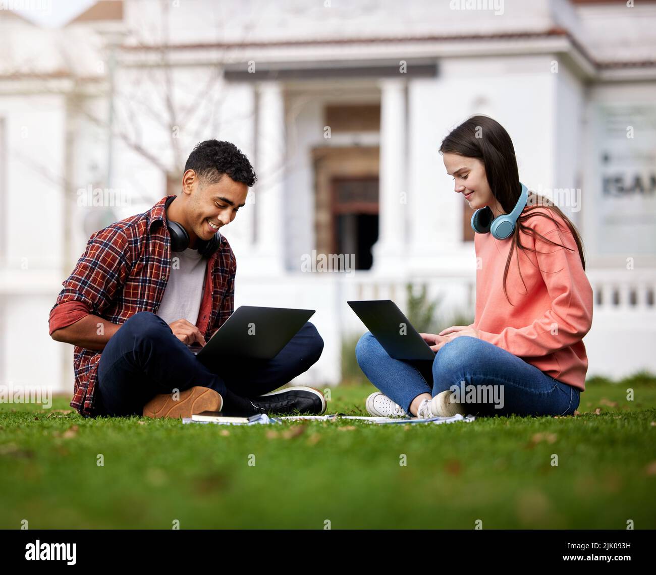 Wir helfen uns immer gegenseitig. Zwei Studenten benutzen ihre Laptops, während sie draußen auf dem Campus sitzen. Stockfoto