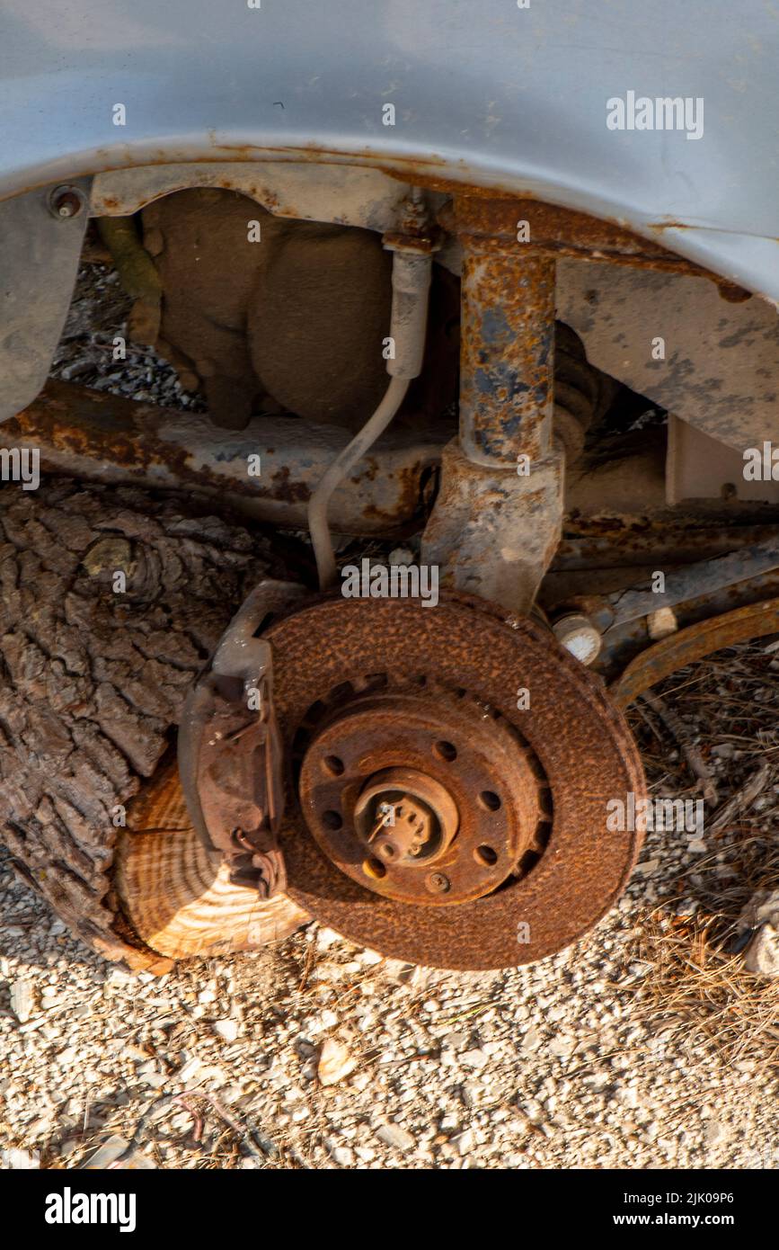 Rostige alte Bremsscheibe, die Elementen auf einem Altauto ausgesetzt ist, alte Autoteile korrodieren, Stoßdämpfer und Bremstrommel sind mit Rost bedeckt und korrodiert. Stockfoto