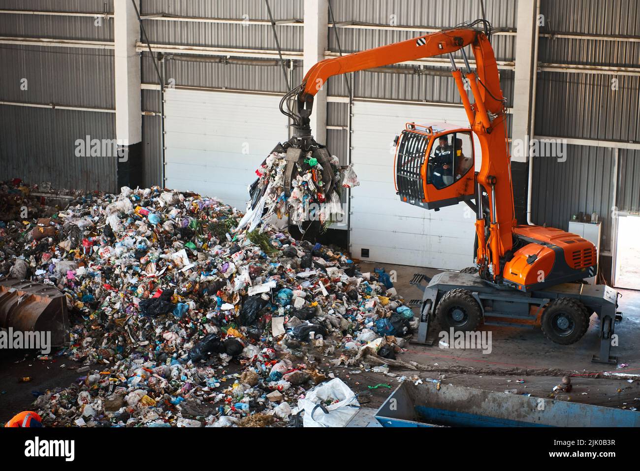 Bagger in der Nähe des Müllhaldes im Lagerhaus des Werks greifen Stockfoto