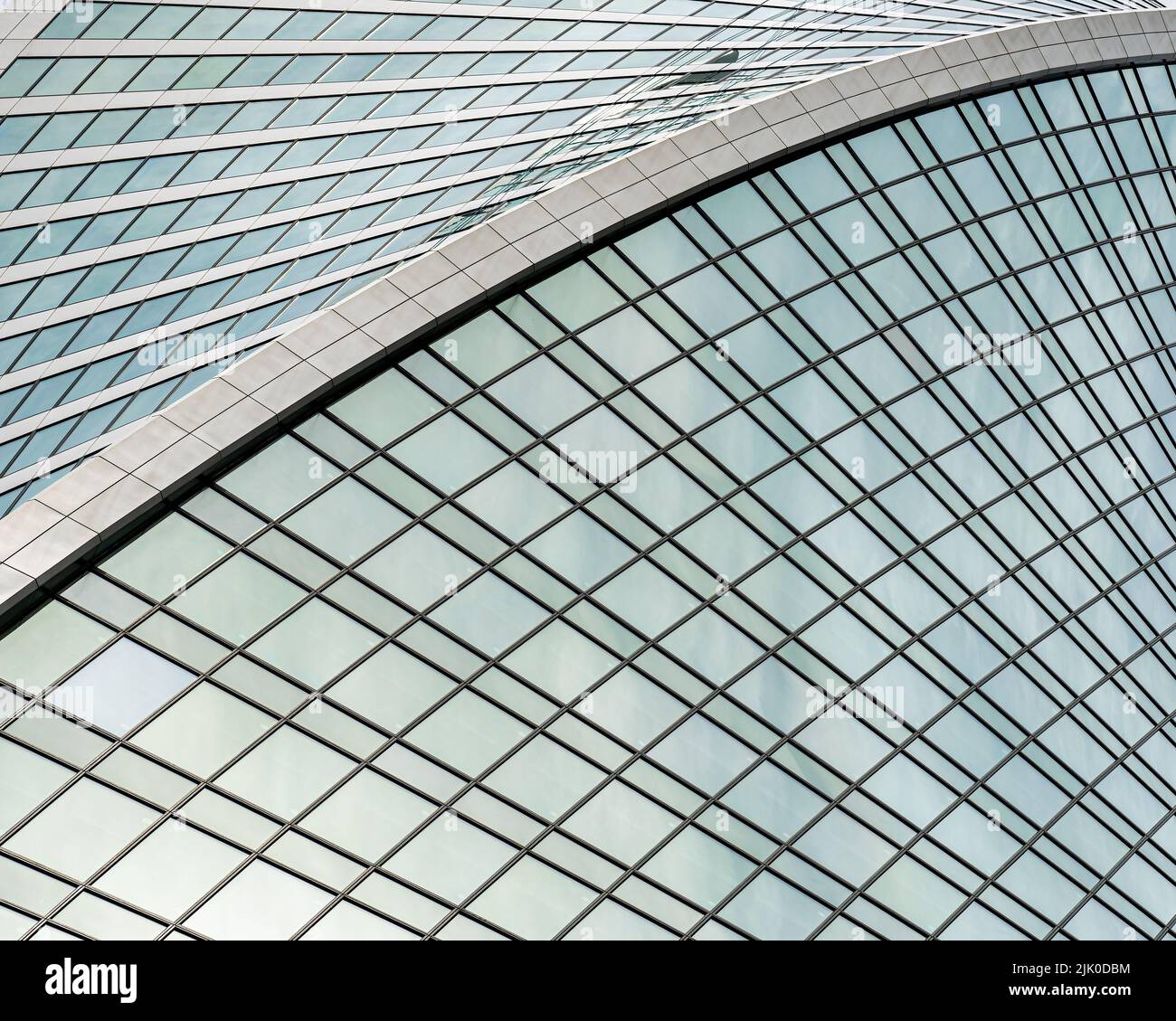 Fragment eines modernen Bürogebäudes. Abstrakter geometrischer Hintergrund. Teil der Fassade eines Wolkenkratzers mit Glasfenstern. Stockfoto
