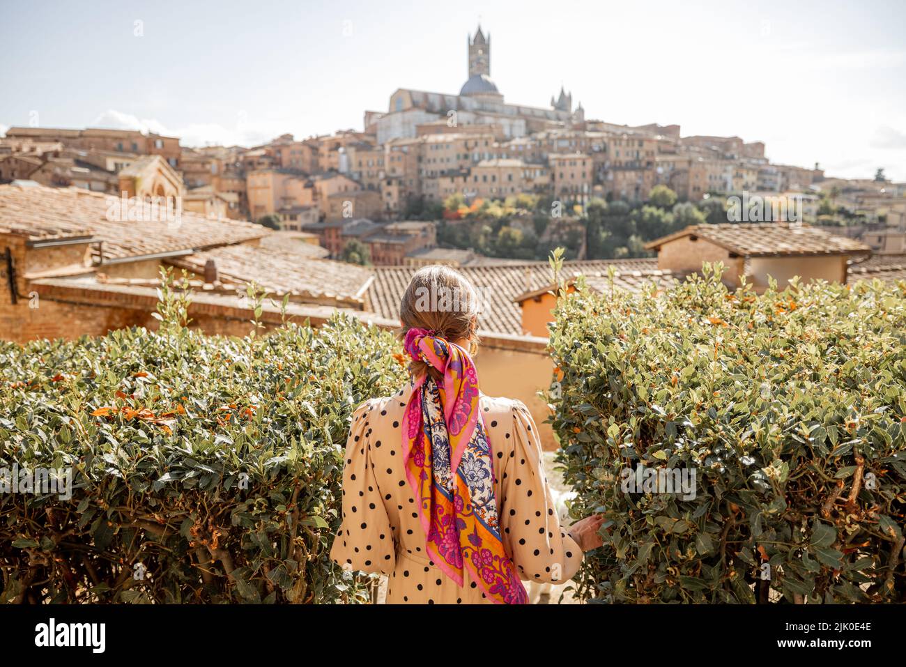 Frau geht vor dem Hintergrund des Stadtbildes der Altstadt von Siena in Italien Stockfoto