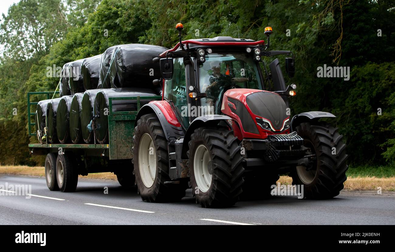 Valtra Schlepper mit einem Anhänger voller Silageballen Stockfoto