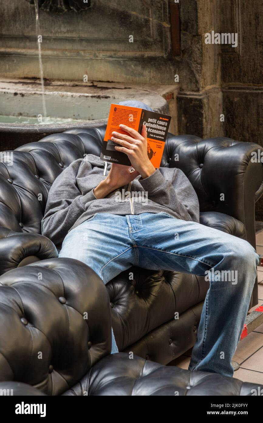 Der Mann, der eine Wirtschaftsabhandlung las, sackte auf einem Sofa. Stockfoto