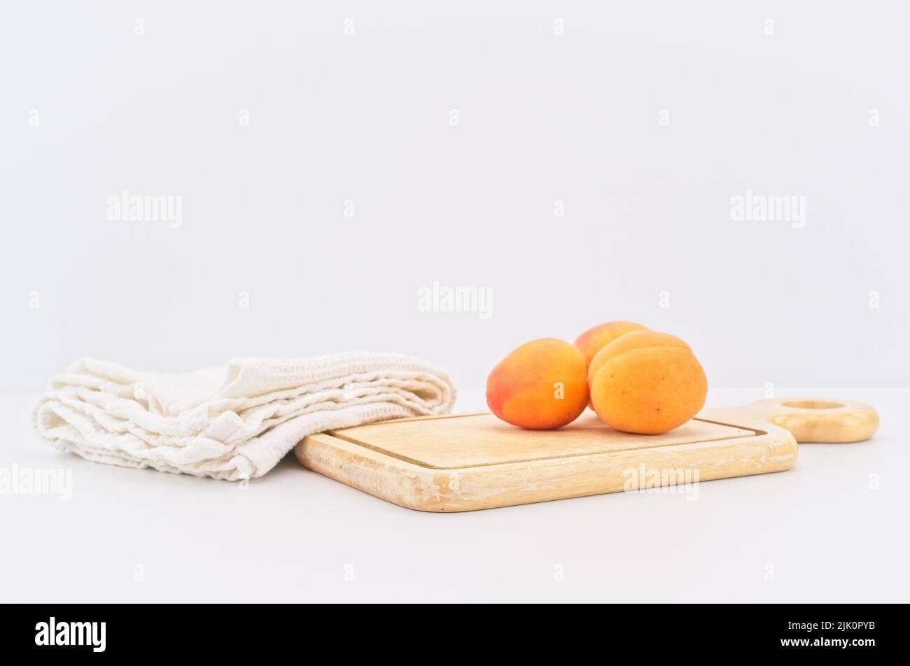 Frische Bio-Aprikosen auf einem Holzschneidebrett mit weißem Küchentuch Stockfoto