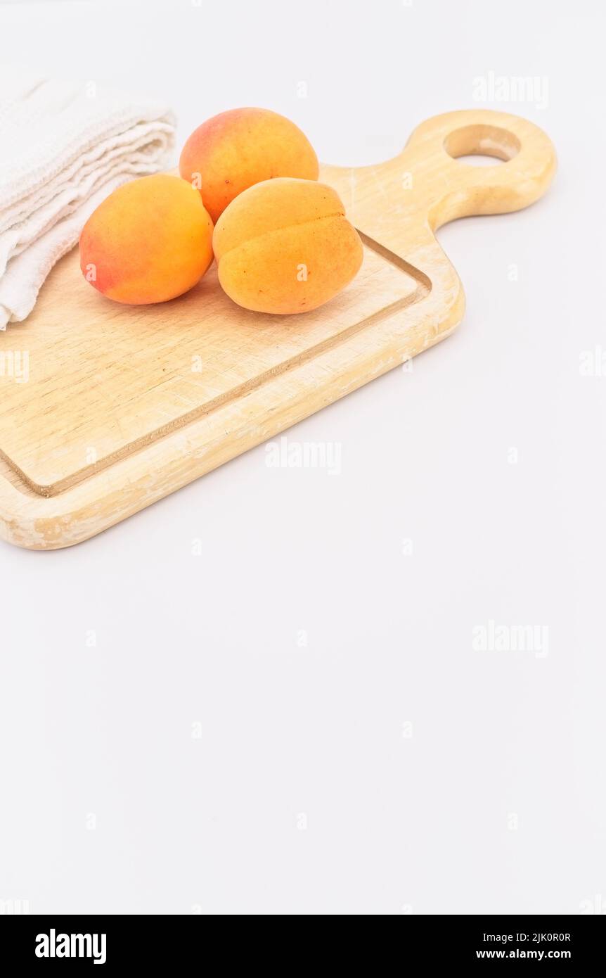 Frische Bio-Aprikosen auf einem Holzschneidebrett mit weißem Küchentuch Stockfoto