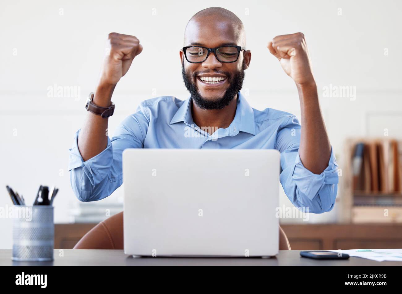 Ich habe es wieder getan. Ein Geschäftsmann, der fröhlich aussagt, als er in seinem Büro an seinem Laptop arbeitete. Stockfoto