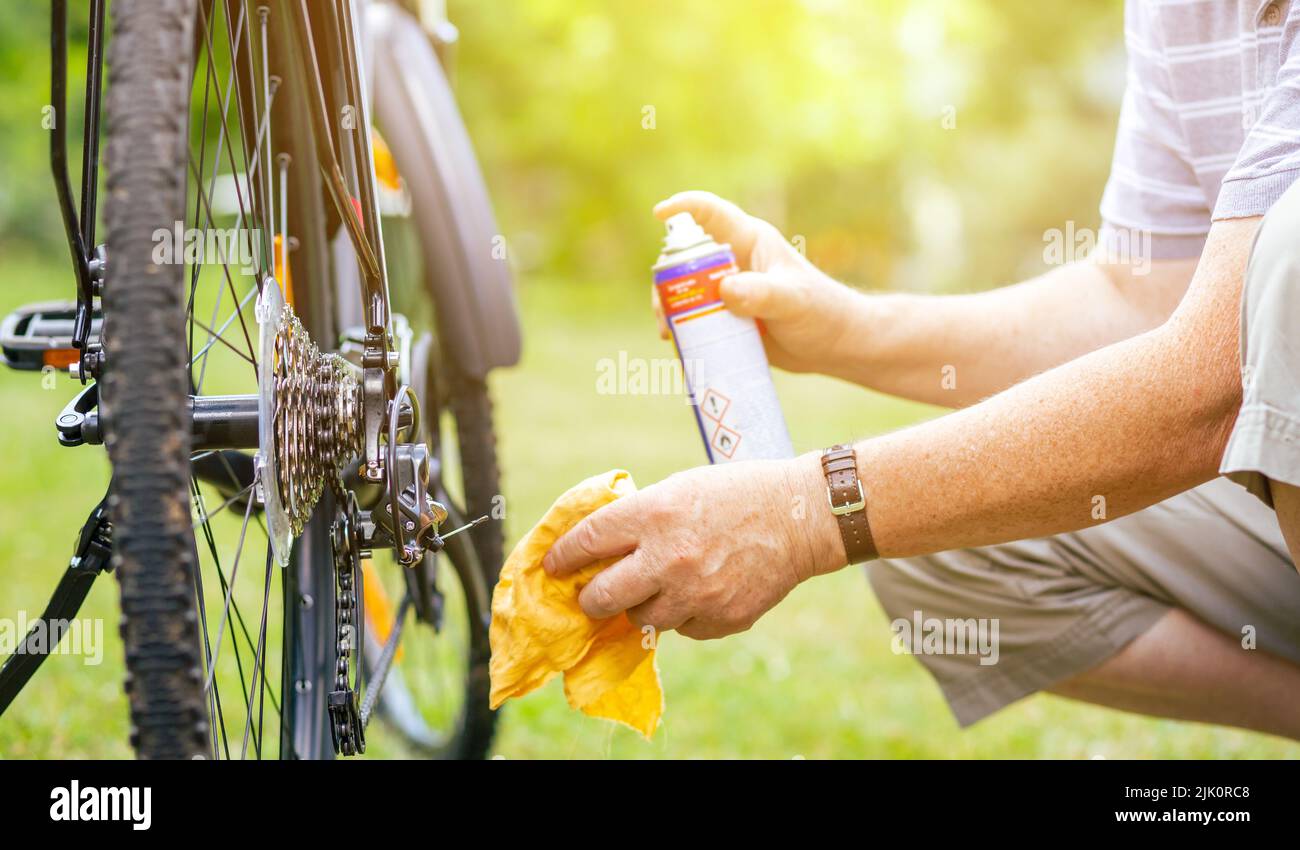 Älterer Mann, der während der Sommerzeit Wartungsarbeiten an seinem Fahrrad machte, seine Kette des Fahrrads ölte, gesunder Lebensstil Stockfoto