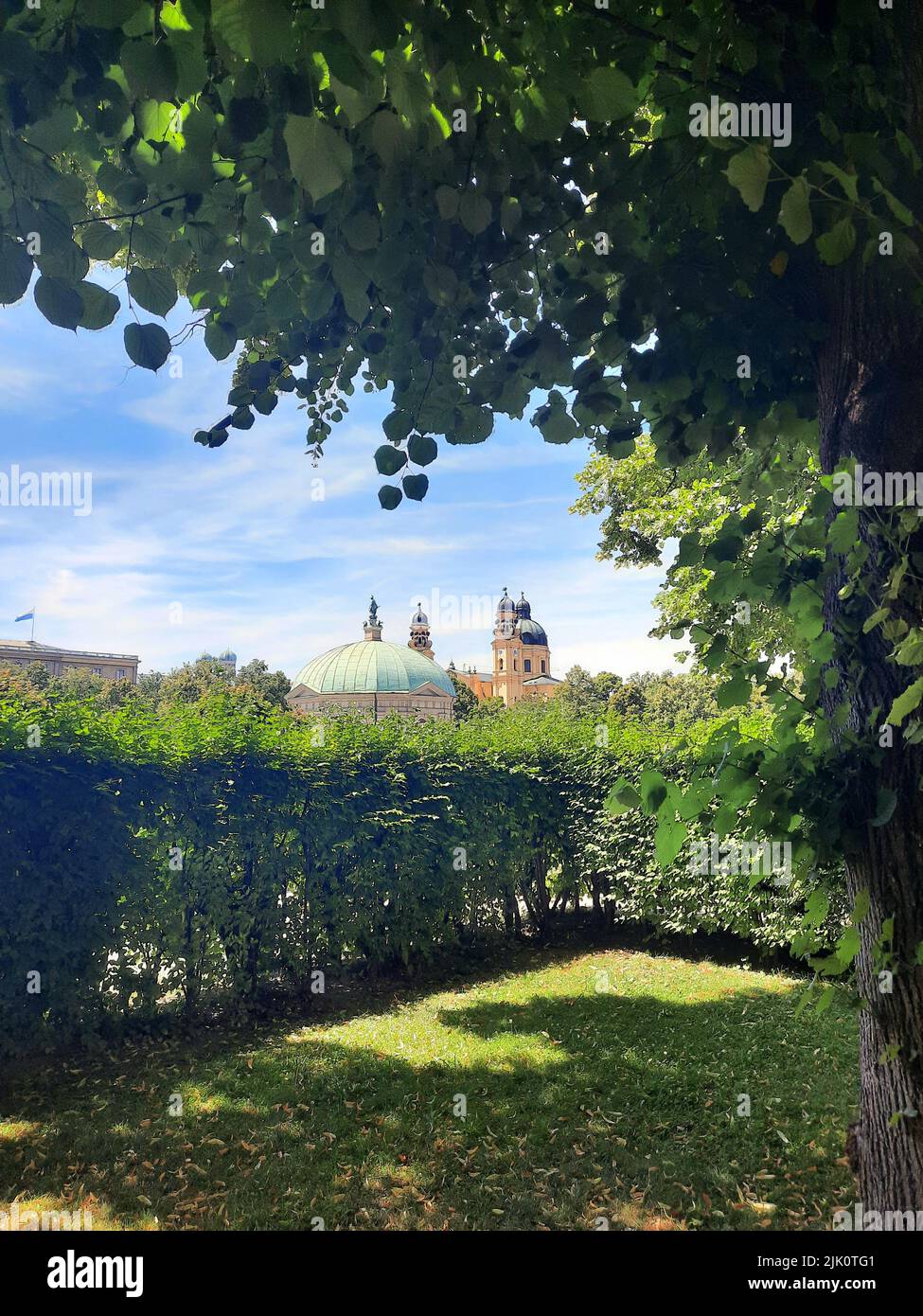 Eine Vertikale eines grünen Gartens vor dem Pavillon im Hofgarten und der Theatinerkirche in München, Bayern, Deutschland Stockfoto