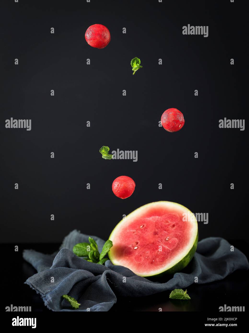 Eine halbe Wassermelone und fliegende Melonenkugeln Stockfoto