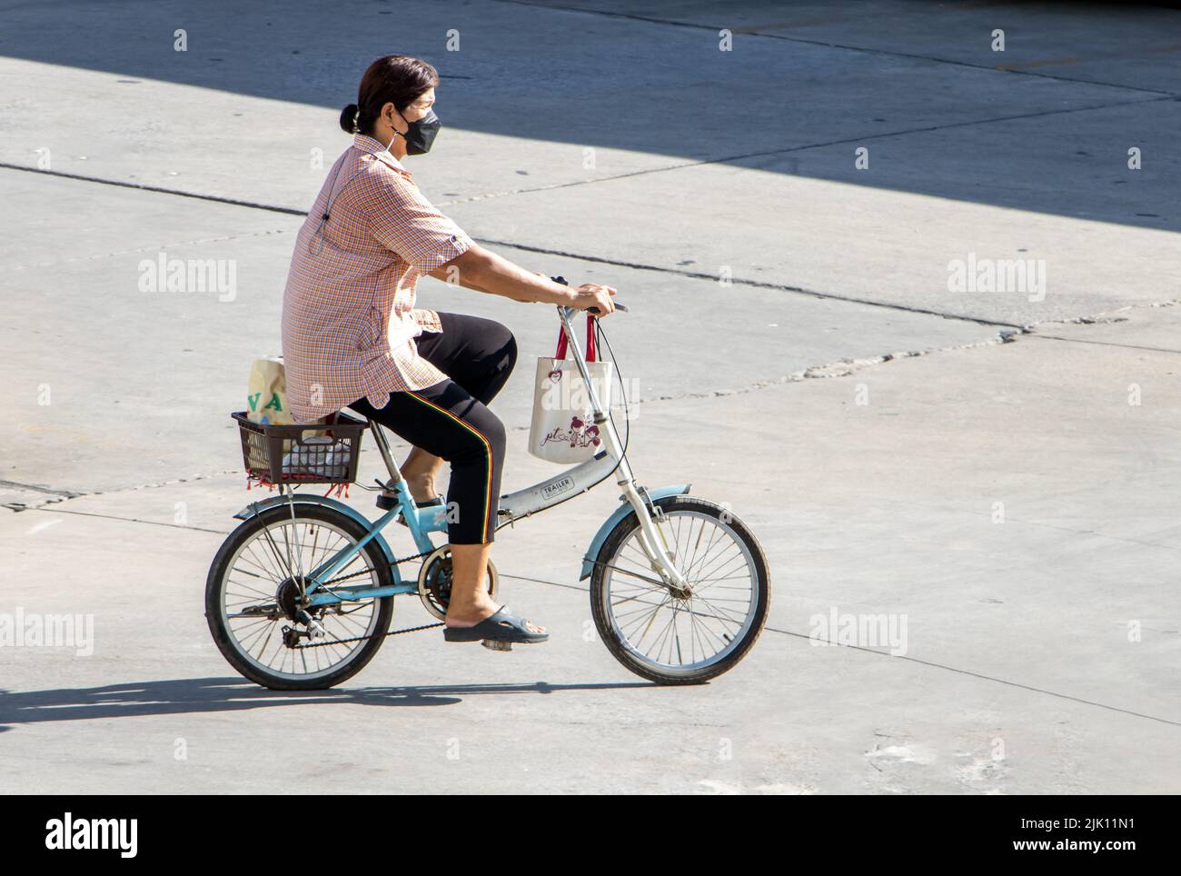SAMUT PRAKAN, THAILAND, MAI 26 2022, Eine Frau fährt auf einem Fahrrad auf der Stadtstraße. Stockfoto