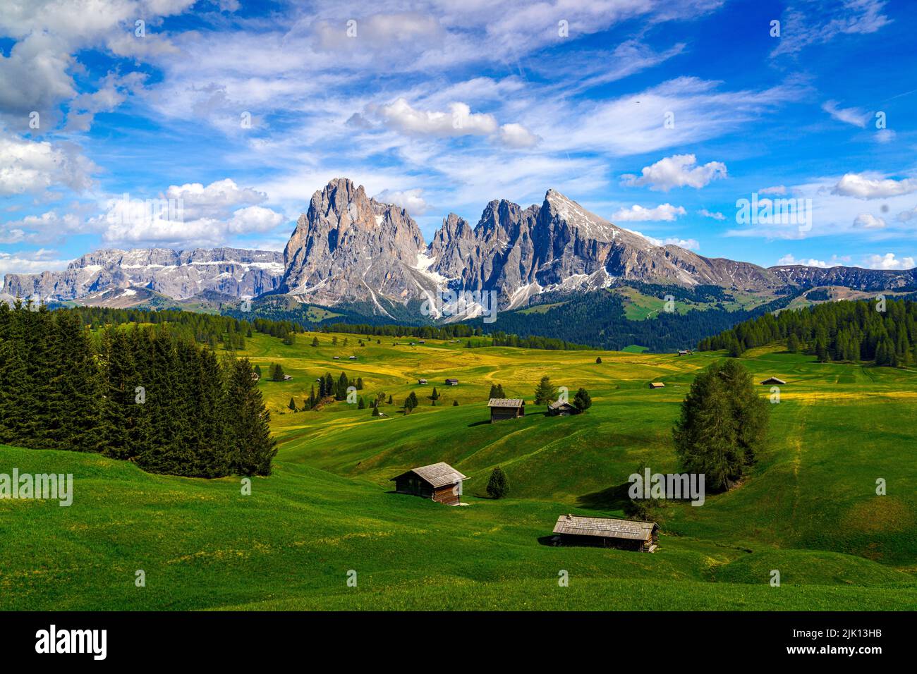 Berghütten auf den grünen Weiden am Fuße des Langkofels und des Sassopiatto im Frühjahr, Seiser Alm, Dolomiten, Südtirol, Italien, Europa Stockfoto