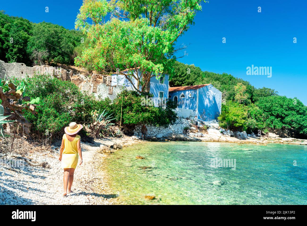 Frau, die auf weißen Kieselsteinen eines von Bäumen umgebenen Strandes läuft, Porto Atheras, Kefalonia, Ionische Inseln, griechische Inseln, Griechenland, Europa Stockfoto