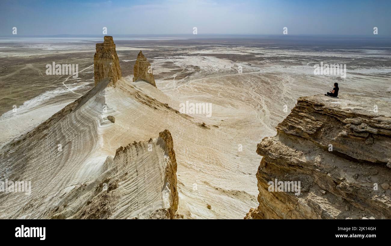 Frau, die auf einer riesigen Felsklippe sitzt, Bozzhira Canyon, Ustyurt-Hochebene, Mangystau, Kasachstan, Zentralasien, Asien Stockfoto