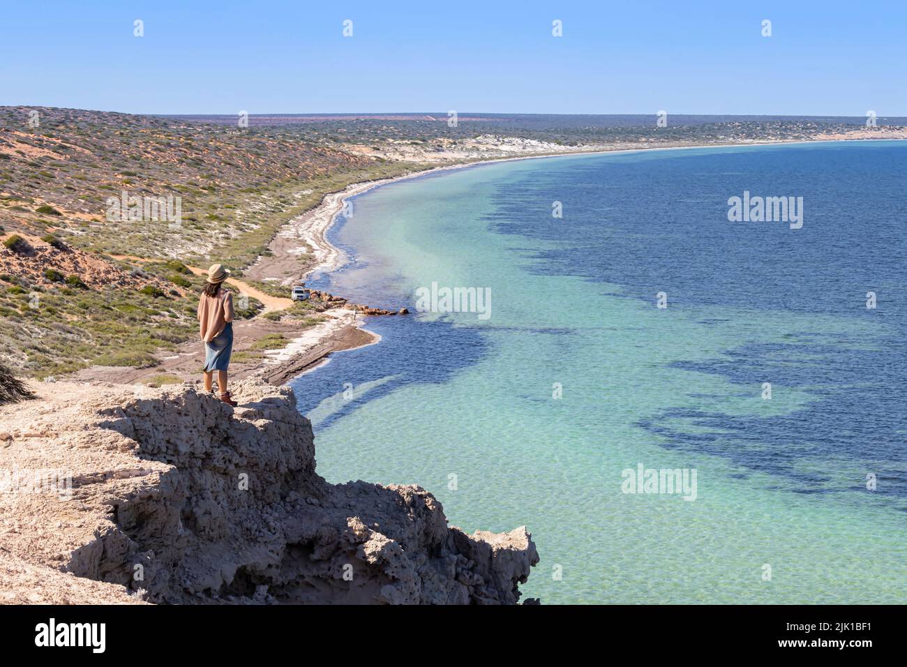 Eine Frau blickt auf das wunderschöne Wasser von Eagle Bluff, Denham, Shark Bay, Westaustralien Stockfoto