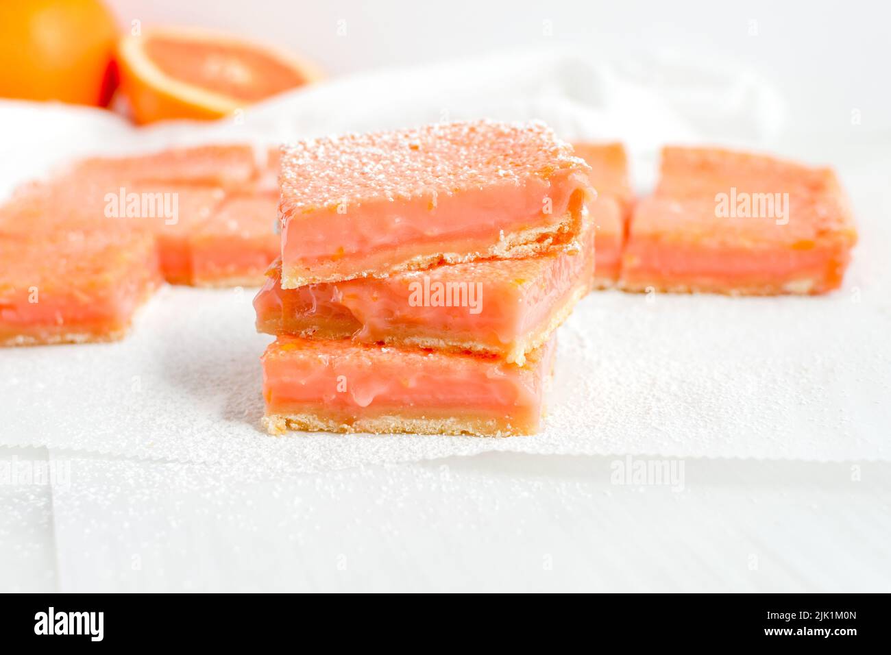 Pink Grapefruit Dessertbars mit Puderzucker garniert: Ein Stapel süßer Dessertbars mit rotem Grapefruitsaft Stockfoto
