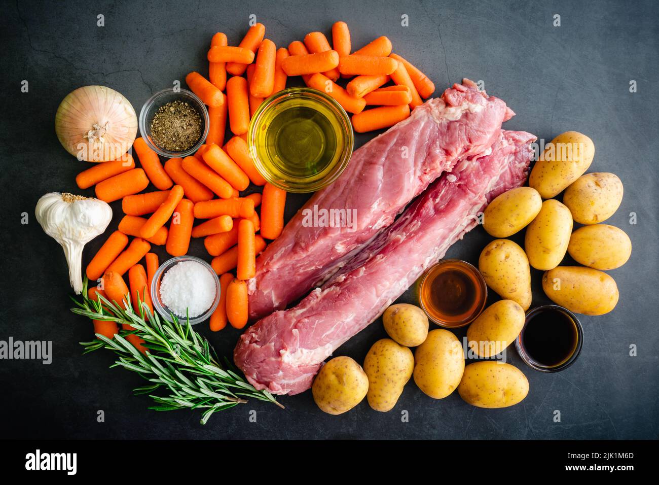 Schweinebraten-Tenderloin mit Kartoffeln und Baby-Karotte Zutaten: Rohes Schweinefilet, Babykartoffeln, frischer Rosmarin und andere Zutaten Stockfoto