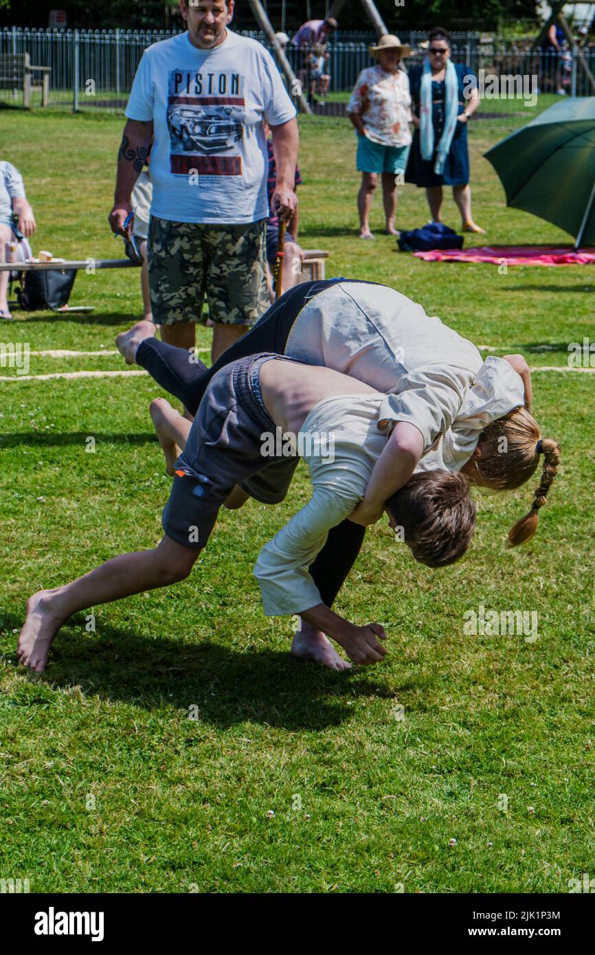 Ein junges Mädchen im Teenageralter, das mit einem Jungen kämpft, der beim Grand Cornish Wrestling Tournament in St. Mawgan in Pydar in Cornwall antritt. Stockfoto