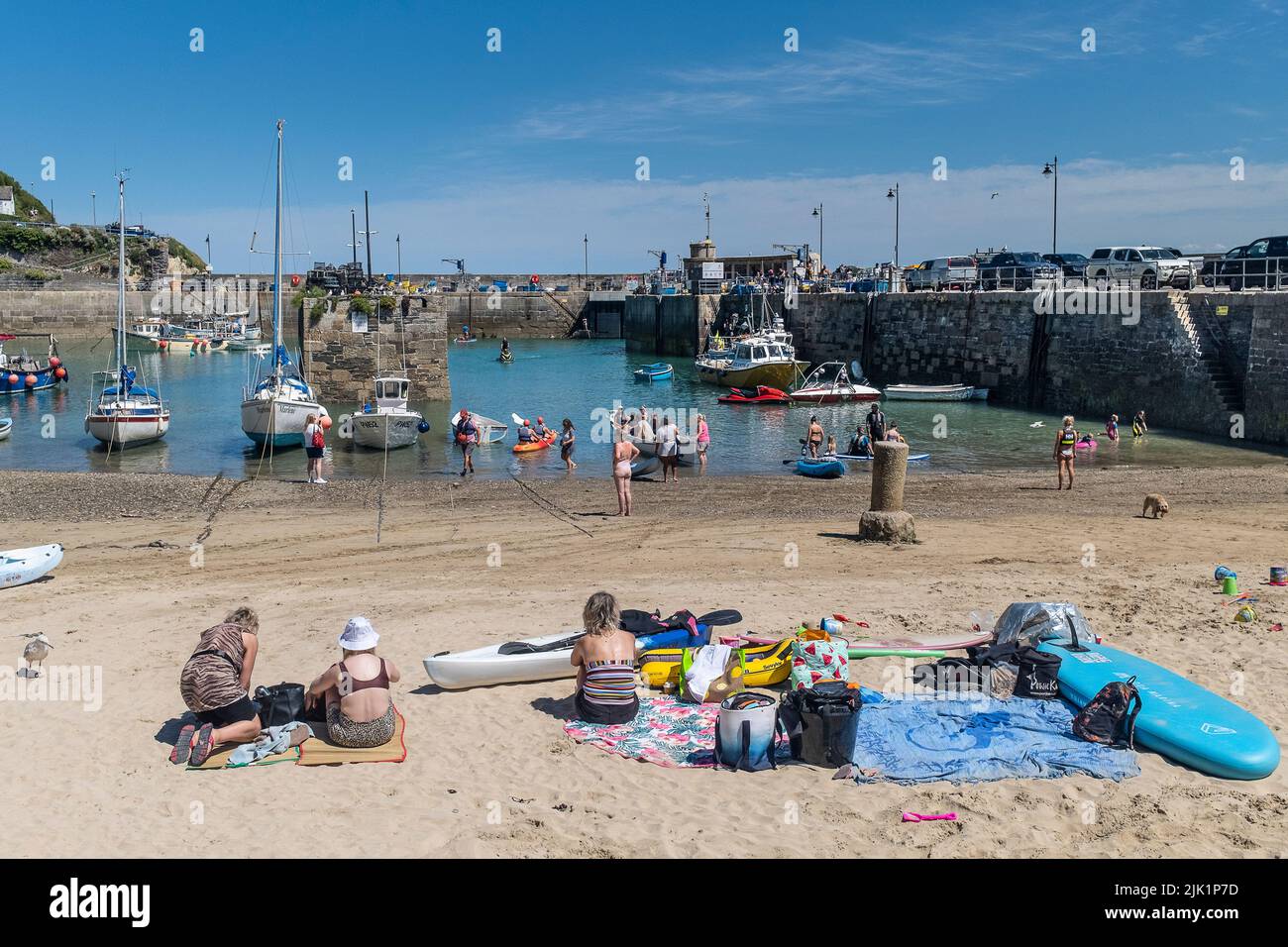 Urlauber genießen den herrlichen Sonnenschein bei einem Aufenthalt im malerischen Newquay Harbour in Cornwall in England im Vereinigten Königreich. Stockfoto