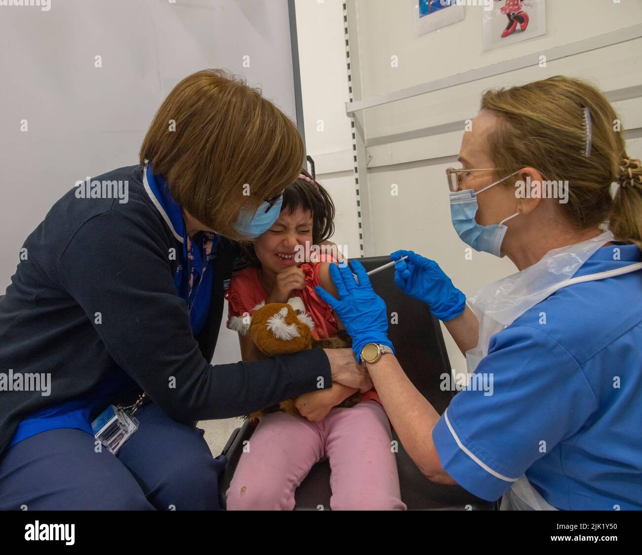 Das Kind erhält von NHS-Mitarbeitern eine kovide Impfung, Großbritannien Stockfoto