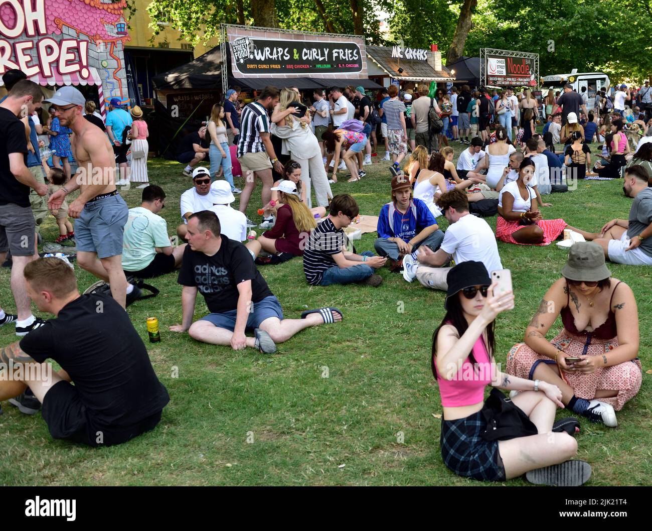 Massen von Menschen, die sich am heißen Sommertag auf dem Rasen im „Queens Square“ neben den Imbissständen entspannen, Bristol Harbour Festival, Großbritannien Stockfoto