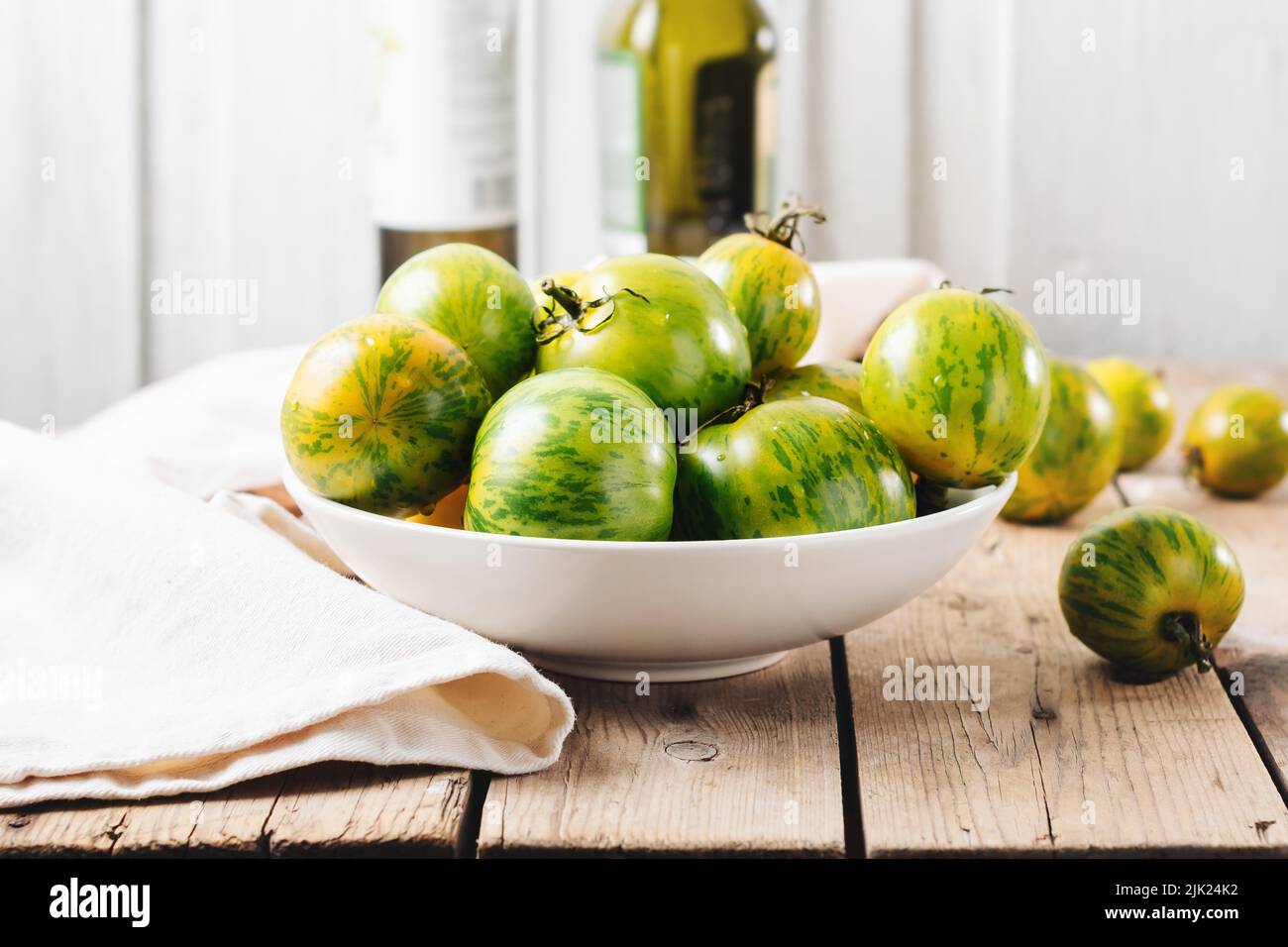 Eine Schüssel mit grünen Tomaten auf einem Holztisch. Stockfoto