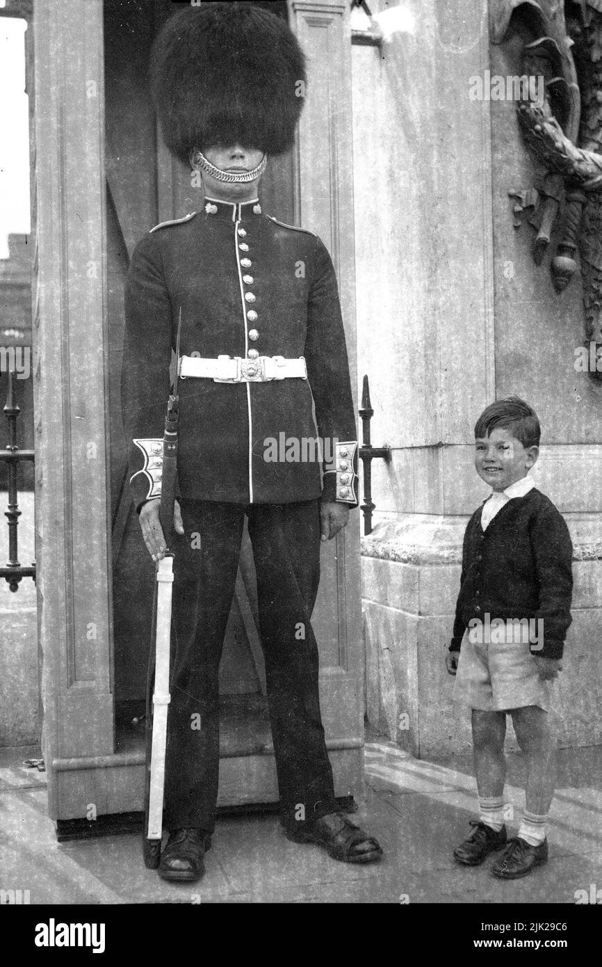 Ein Grenadier-Wachmann im Dienst vor dem Buckingham-Palast, mit einem kleinen Jungen, im Jahr 1954 Stockfoto