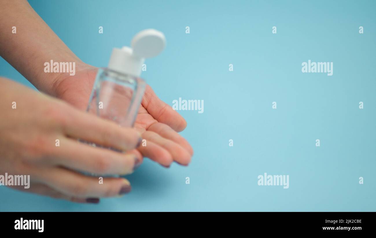 Menschliche Hand Plastikflasche mit Alkoholgel, um die Reinigung zu tun. Isolierter blauer Hintergrund. Das Coronavirus im Jahr 2019 wird den Ausbruch stoppen. Speicherplatz kopieren Stockfoto