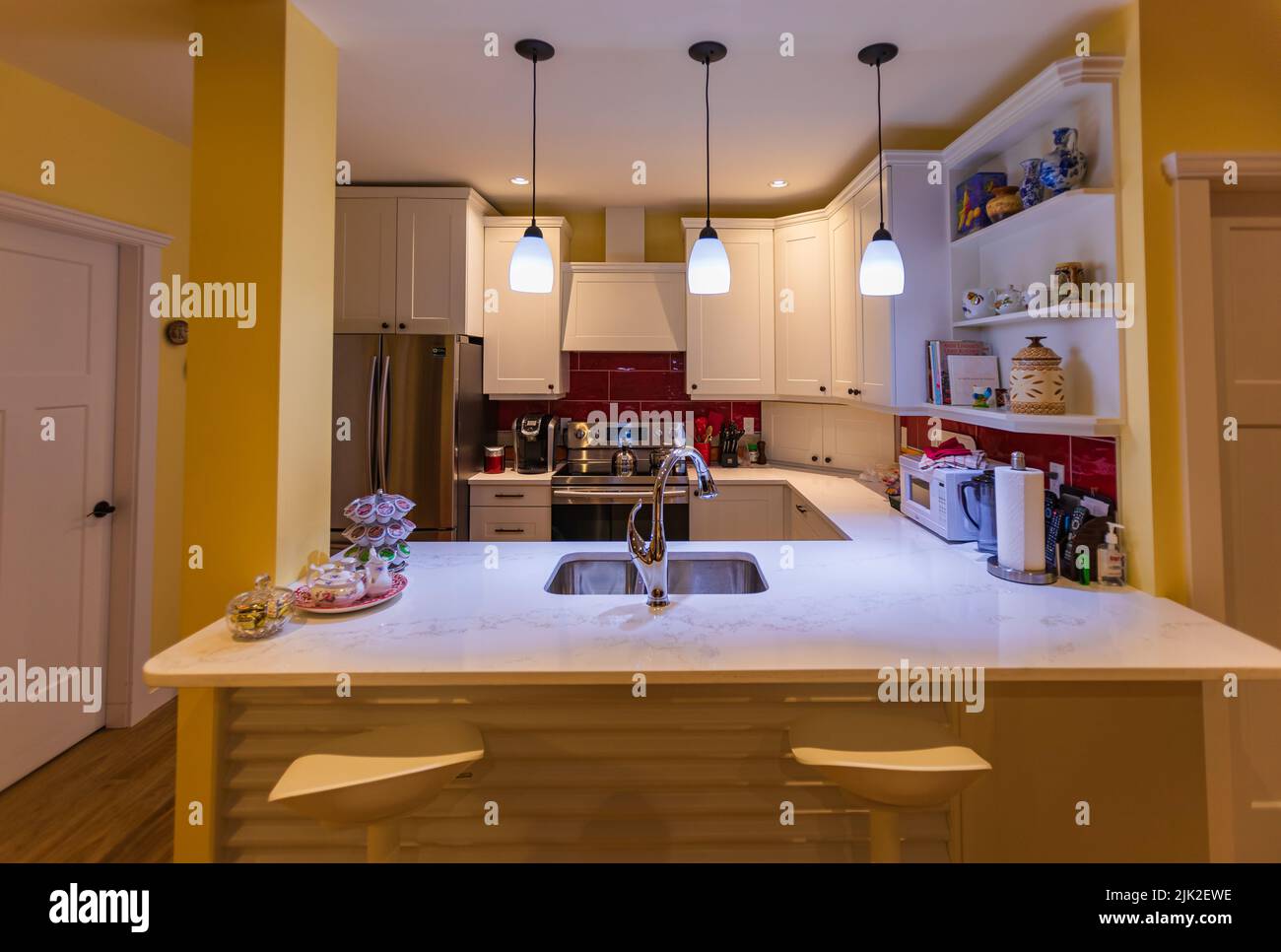 Schöne Küche in Luxus-Haus mit Insel, Pendelleuchten, Schränke. fliesen zurück Spritzer, Edelstahl-Backofen, Herd und Kapuze ergänzen die elegante Stockfoto