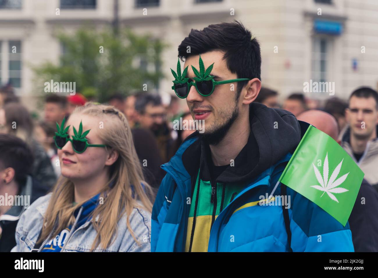 05.28.2022 Warschau, Polen. Zwei kaukasische Demonstranten - ein schwarzhaariger Mann und eine blonde Frau - gingen Schulter an Schulter während eines Pro-Cannabis-marsches und trugen lustige ungrautförmige Sonnenbrillen. Hochwertige Fotos Stockfoto