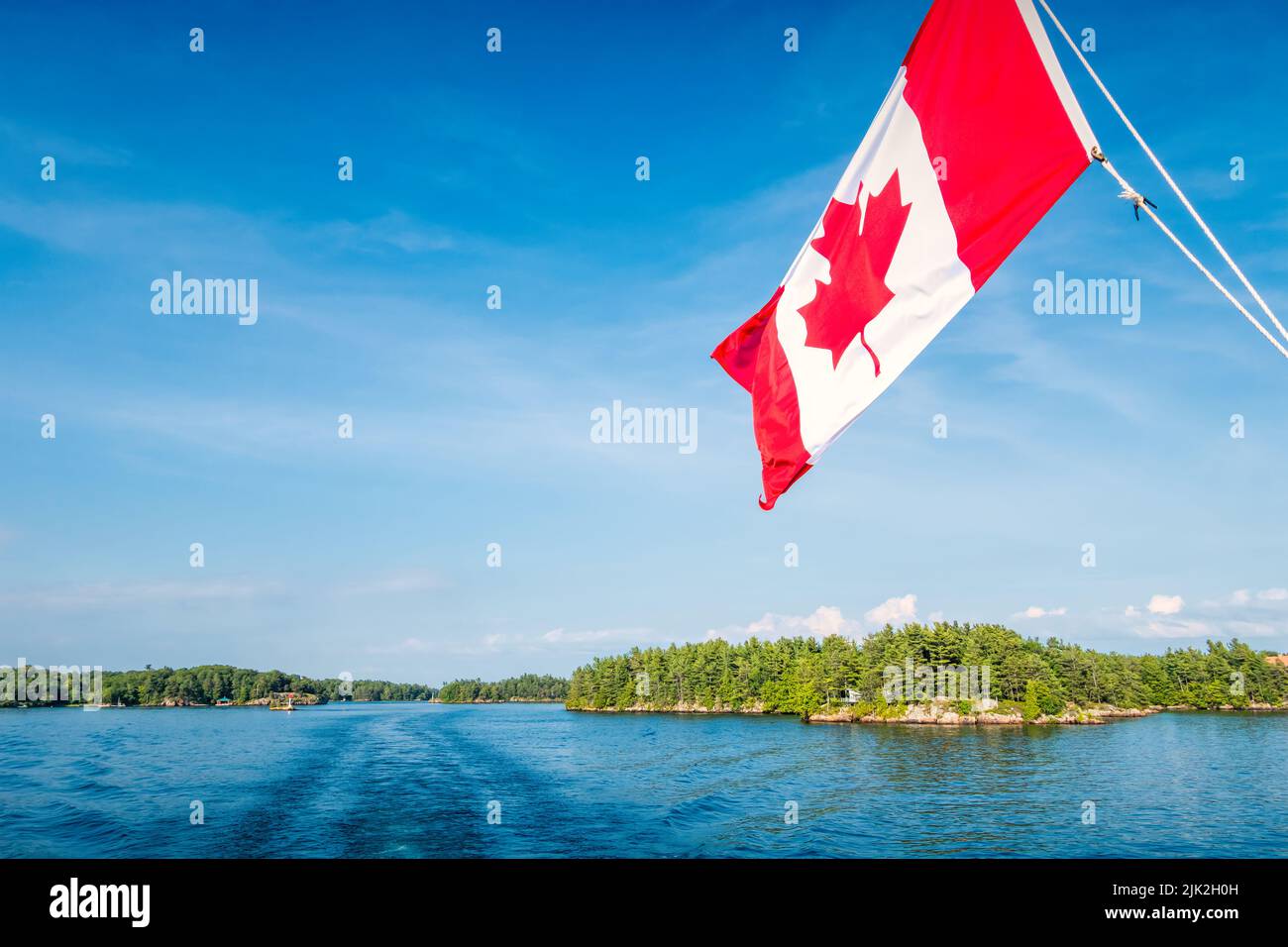 Kanadische Flagge auf einem Tourboot mit Thousand Islands Landschaft und dem St. Lawrence River in Ontario, Kanada. Stockfoto