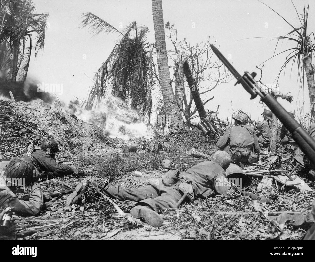 Männer der 7. Division benutzen Flammenwerfer auf japanische Soldaten in einem Blockhaus auf der Insel Kwajalein, während andere mit Gewehren warten, falls andere Japaner herauskommen sollten. Stockfoto