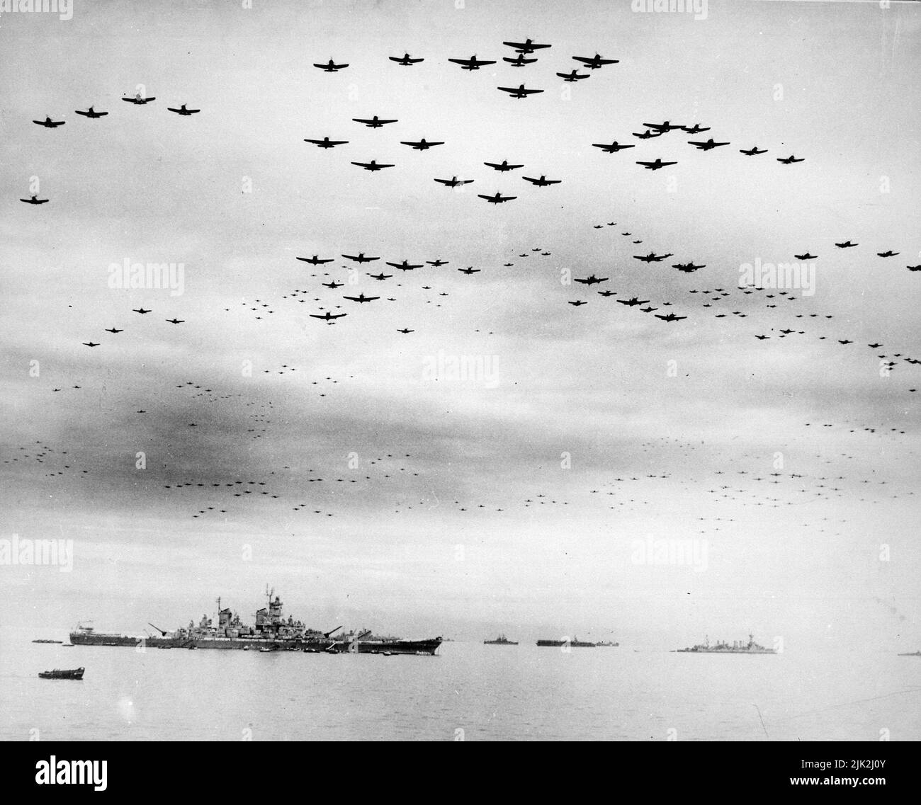 Massierte Formationen von Vought F4U Corsair und Grumman F6F Hellcat Flugzeugen fliegen während der Kapitulationszeremonie am 2.. September 1945 über die Bucht von Tokio. Das Schlachtschiff USS Missouri, auf dem die Kapitulation unterzeichnet wurde, ist das große Schiff direkt links von der Mitte. 9/2/1945 Stockfoto