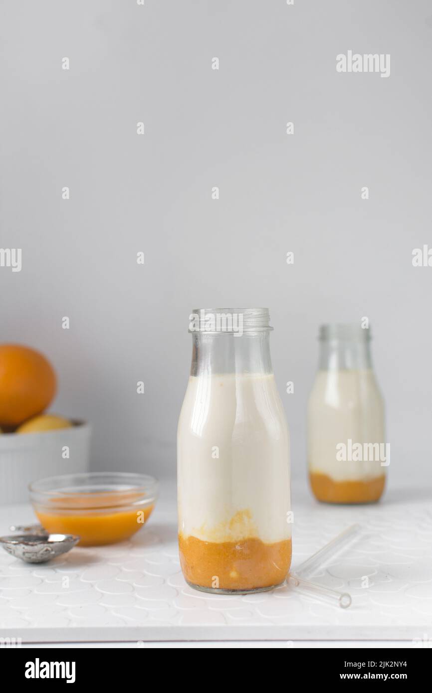 Mango-Milch in einer klassischen Milchflasche, Mango-Püree und Vollmilch in einer transparenten Flasche, Mango-Milchshake Stockfoto