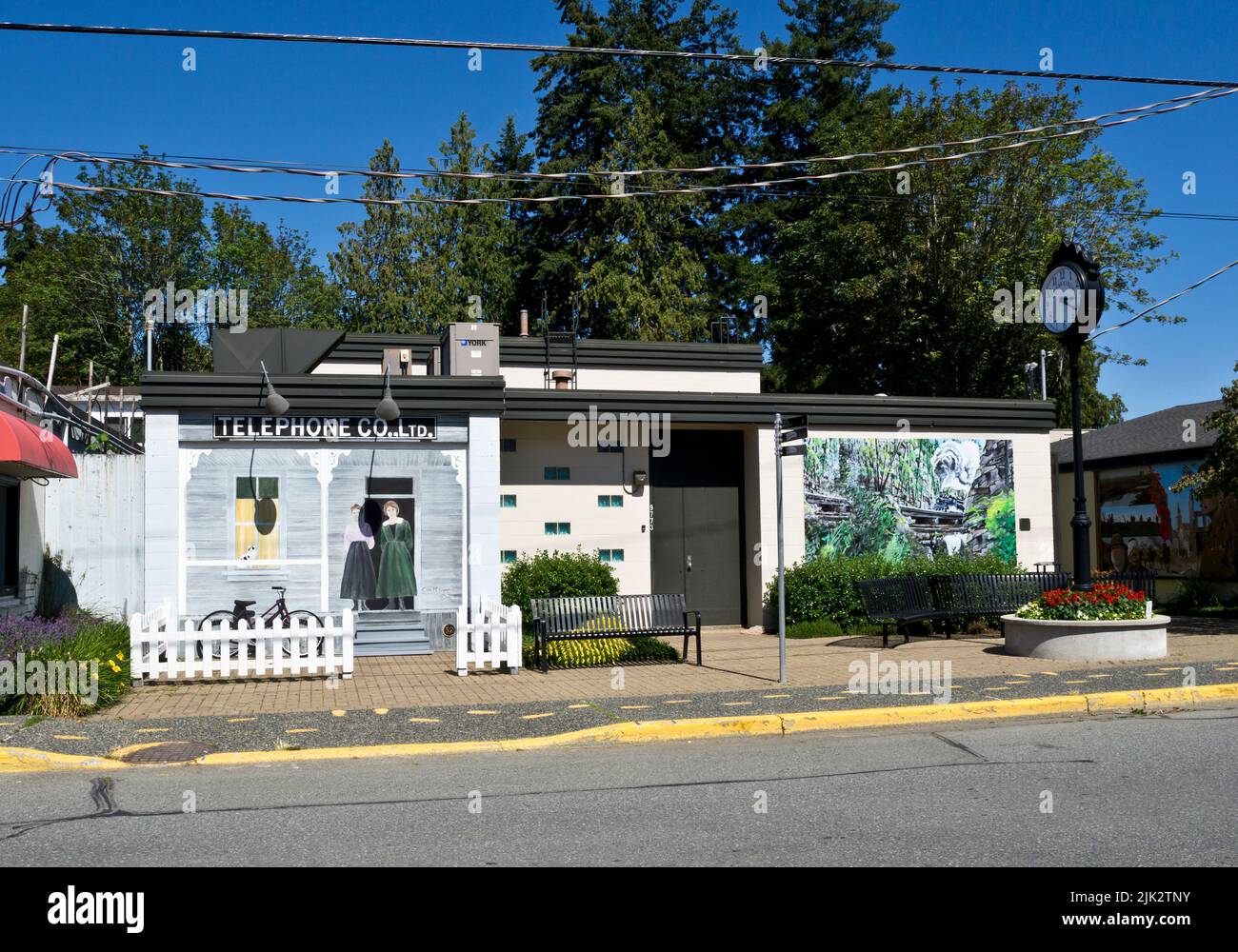 Gebäude in Chemainus, British Columbia, mit zwei Wandmalereien. Ein Wandgemälde ist von der Telefongesellschaft und eines von einer Dampfmaschine (siehe weitere Details) Stockfoto
