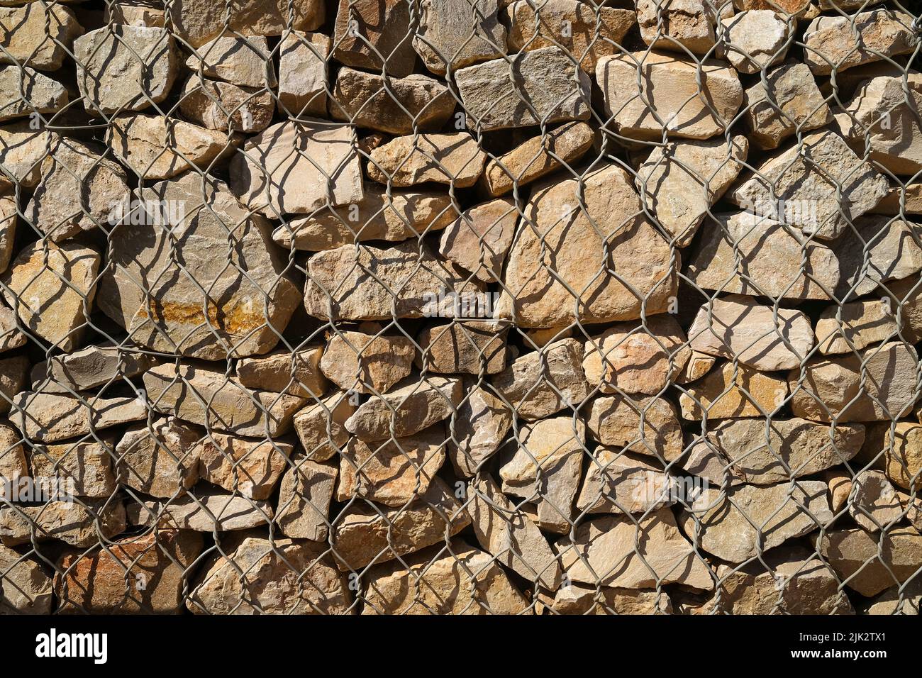 Felsen hinter Hühnerdraht, Gabion-Steinmauer Stockfoto