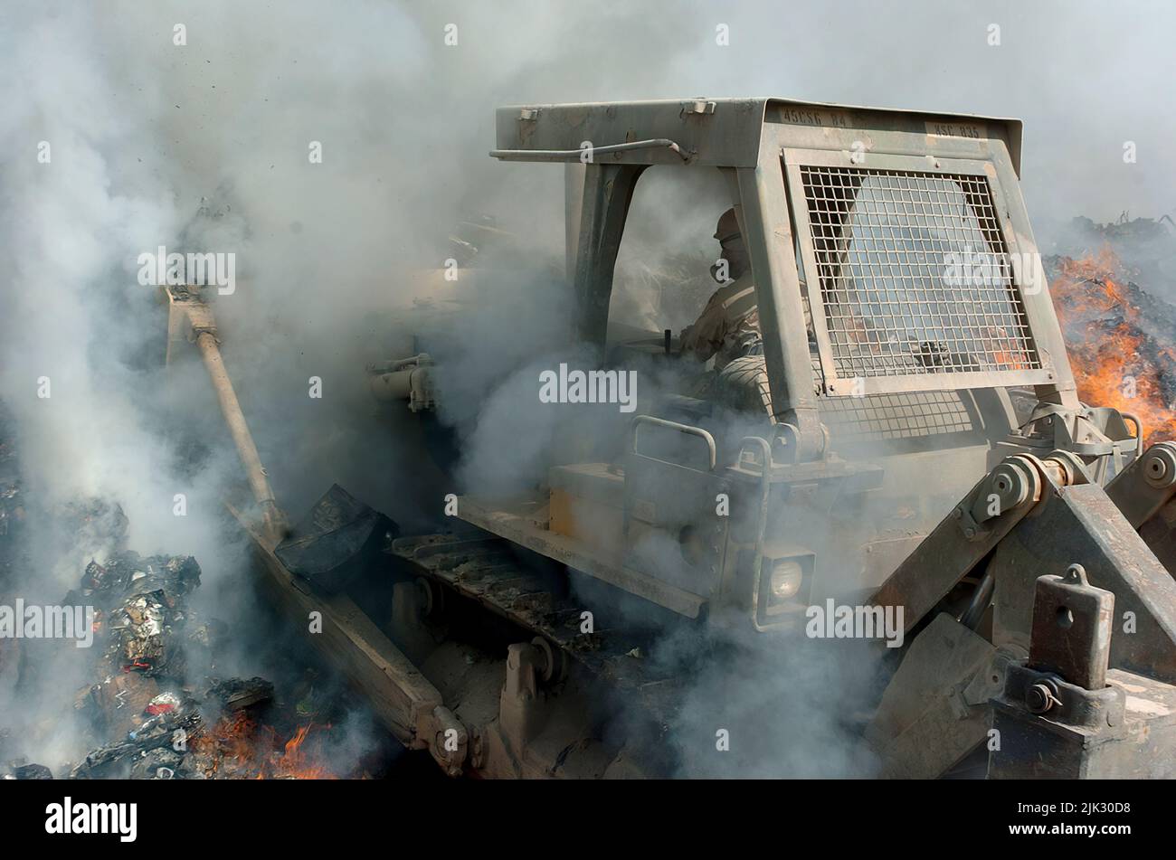 (LOGISTIKBEREICH ANACONDA, Balad, Irak) - Rauch kommt von allen Seiten als Sgt. Richard Ganske, Bataillon des Kampfingenieurs von 84., schiebt den Bulldozer tief in die Flammen der Brandgrube, um brennbare Gegenstände ständig in Flammen zu halten und sie zu entsorgen, damit sie den Posten nicht aufwirren. Bulldozer und Bagger sind die schweren Geräte, die von den 84. EN Mrd. verwendet werden, um Müll in der Brandgrube zu verwalten. Stockfoto