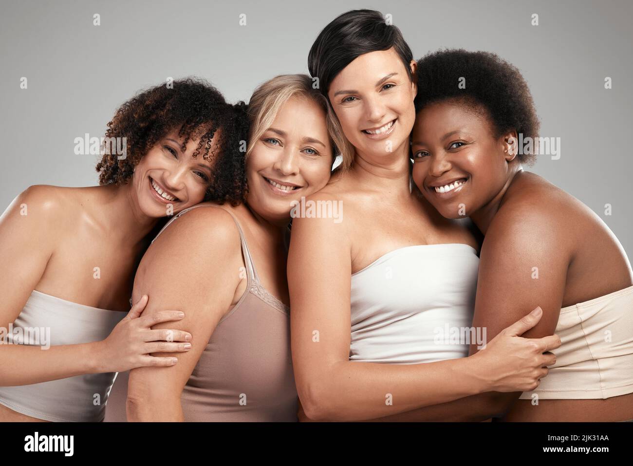 Frauen, die zusammen stehen, gewinnen zusammen. Eine vielfältige Gruppe von Frauen steht und umarmt sich im Studio. Stockfoto