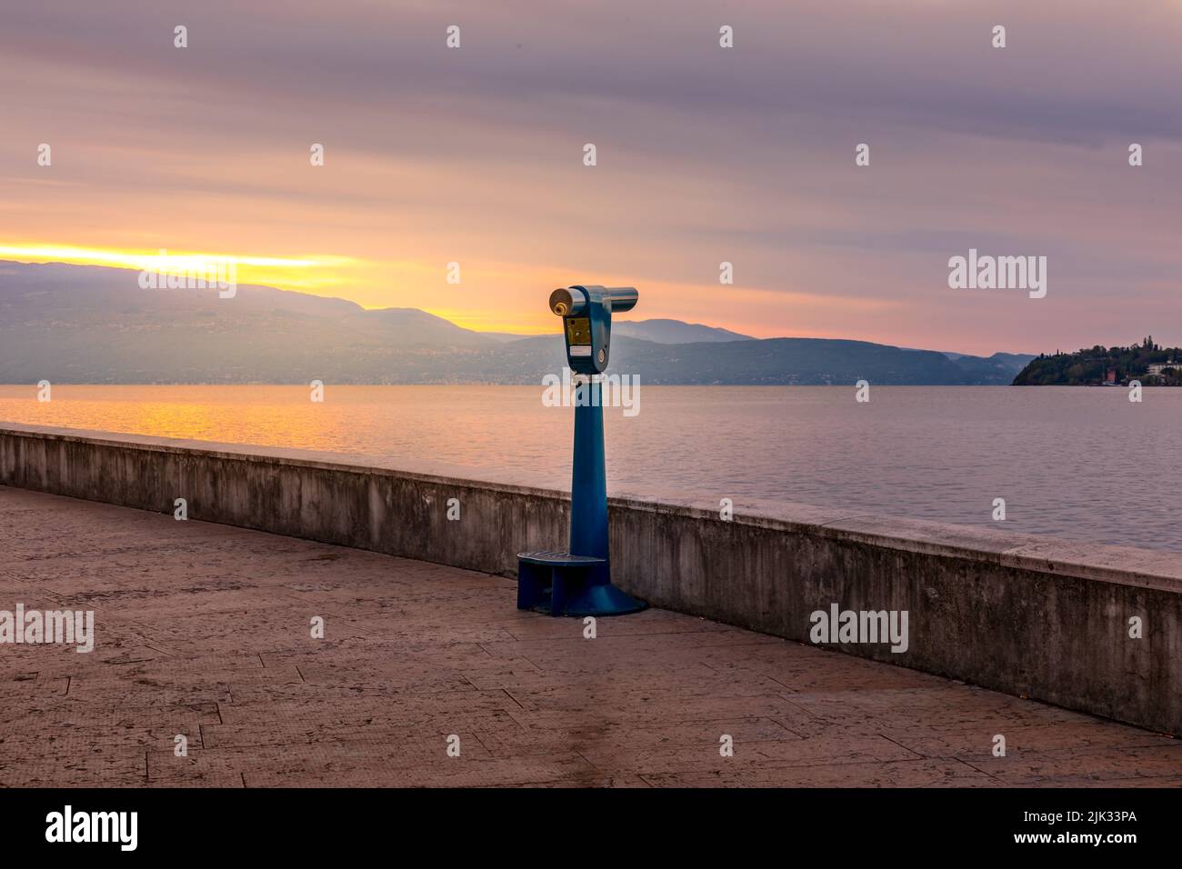 Sonnenaufgang über dem Gardasee, Ferngläser warten auf Touristen, um einen Blick über den See zu werfen Stockfoto